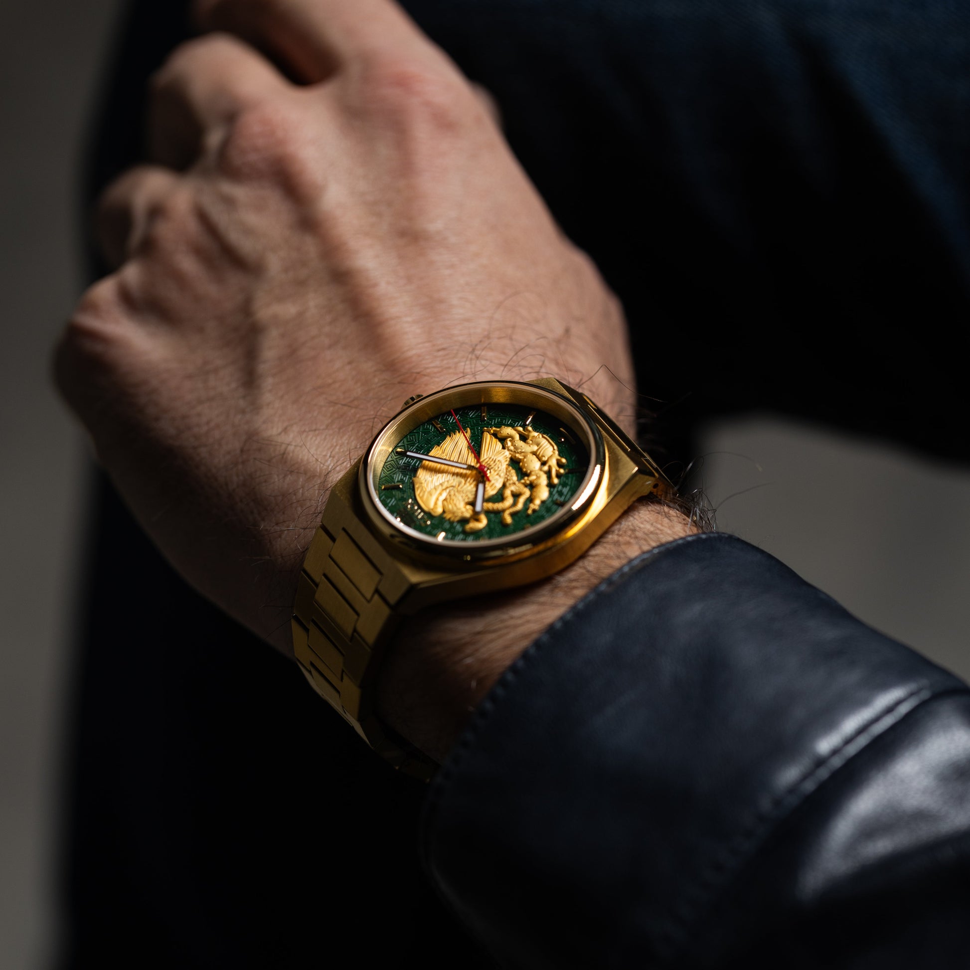 Mexican eagle watch with green face on a wrist, wearing a dark jacket